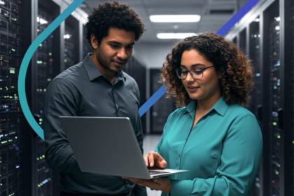 Dois profissionais de TI em um data center analisam configurações de servidores em um laptop. A imagem ilustra a colaboração em tarefas de infraestrutura e segurança, focando na otimização de sistemas digitais.